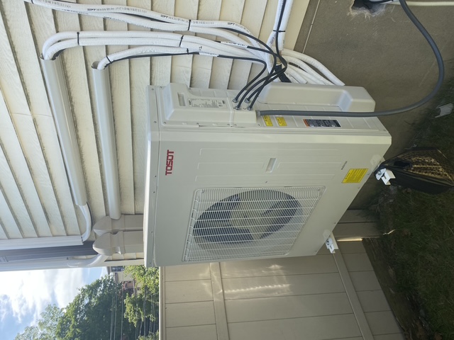 Outdoor ductless mini-split condenser installation beside a home
