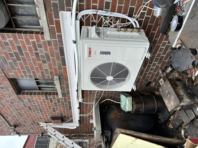 Outdoor mini-split condenser mounted to a brick exterior