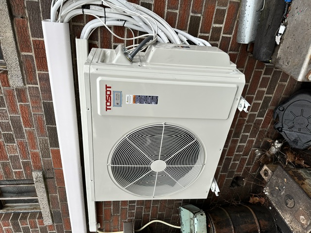 Outdoor ductless mini-split condenser mounted on a brick wall