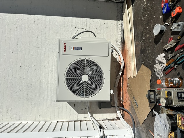 Outdoor ductless mini-split condenser installation on a light exterior wall